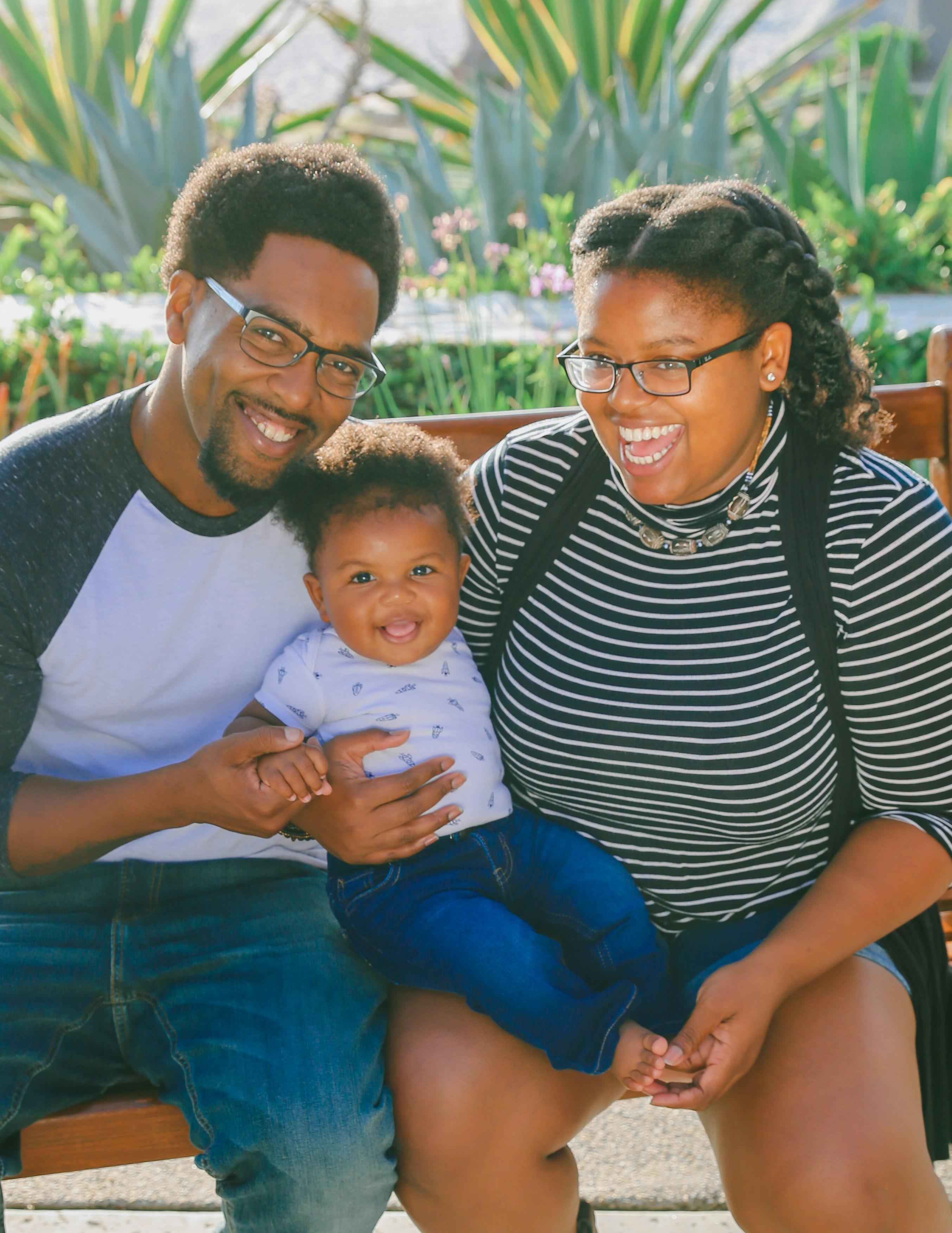 Smiling mother and father sitting on a bench holding their baby son
